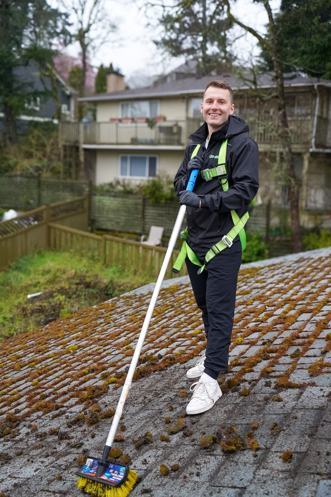 Craig from Shine standing on a mossy roof with a brush